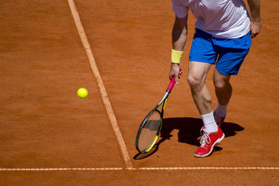 Low section of man playing tennis on court