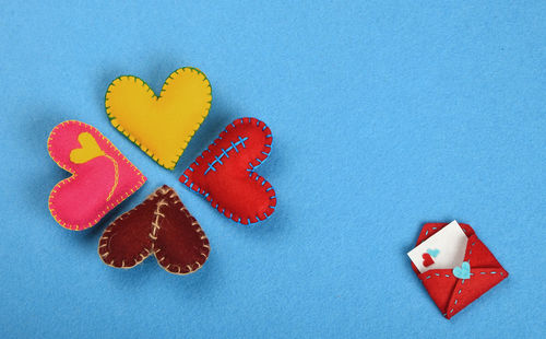 High angle view of colorful heart shapes art arranged on blue background