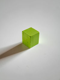 Close-up of green toy on wood against white background
