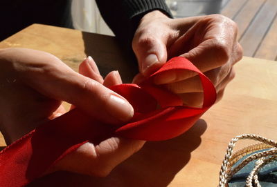 Cropped hands of person tying ribbon on table