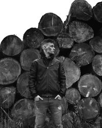 Man standing against stacked logs