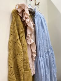 Close up of clothes in blue, ochre and pink colour hanging on a hook.