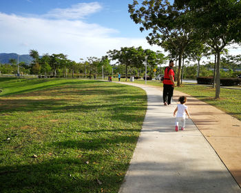 Full length of father and daughter waking on footpath at park