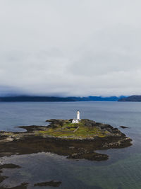 Lighthouse by sea against sky