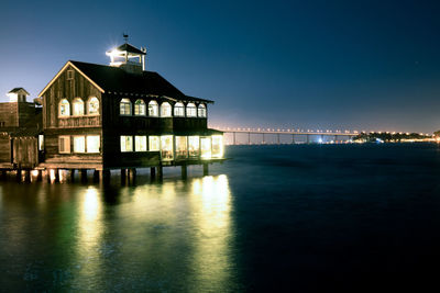 Building by sea against clear blue sky at night