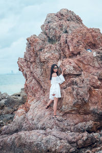 Portrait of woman standing on rock by sea