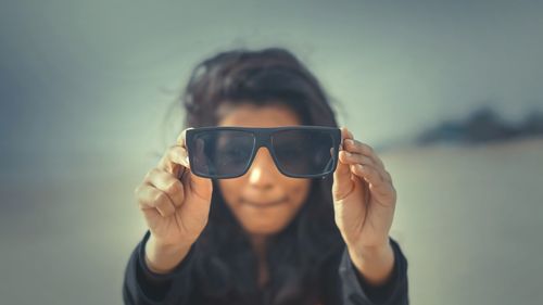 Close-up portrait of a smiling young woman against sky