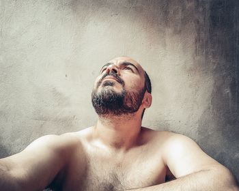 Portrait of shirtless man against wall