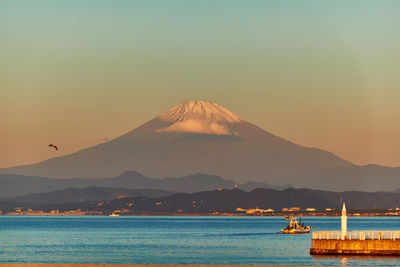 Scenic view of sea and snowcapped mountain against sky during sunrise