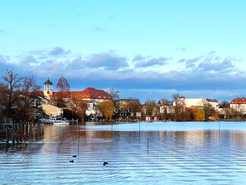 Buildings by sea against sky