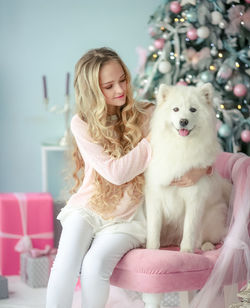 Portrait of young woman with dog sitting on sofa at home
