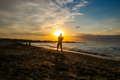 Man playing frisbee on the beach during sunset