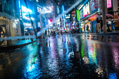 People on wet road in city at night