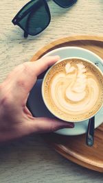 Close-up of hand holding coffee cup on table