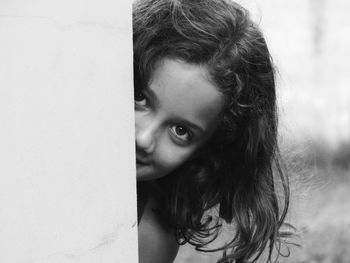 Portrait of girl hiding behind wall