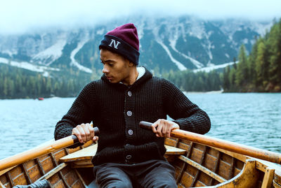 Portrait of young man sitting on boat against lake