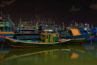 Boats moored in harbor at night