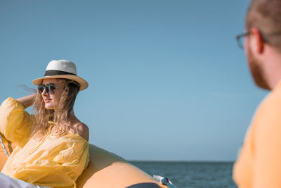 Woman wearing sunglasses sitting in boat on sea against clear sky