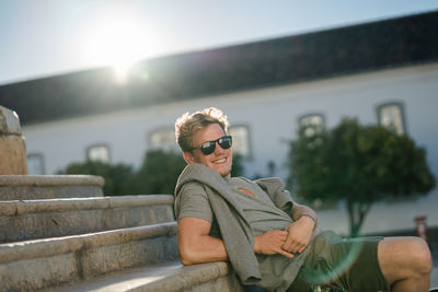 Portrait of young man sitting against built structure