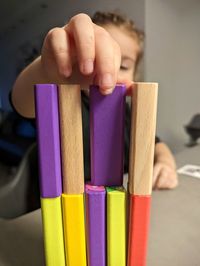 Close-up of hand holding multi colored pencils on table