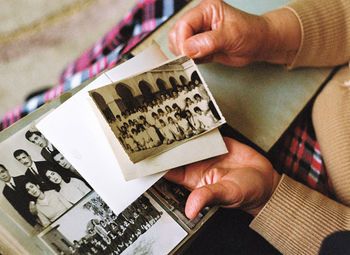 High angle view of man holding paper with old analog photos