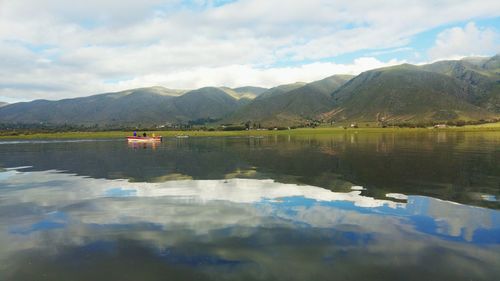Scenic view of lake by mountains against sky