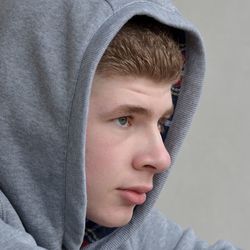 Close-up of thoughtful man in gray hooded shirt looking away