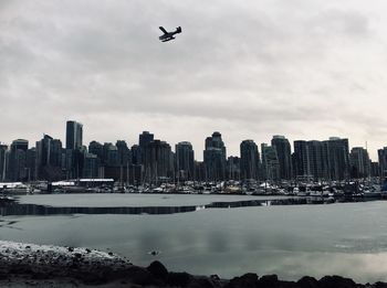 Frozen river in city against sky