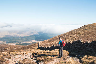 Rear view of man with bicycle on mountain against sky