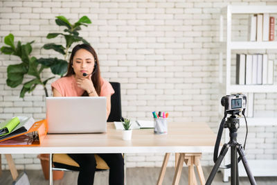 Side view of young woman using mobile phone while standing in office