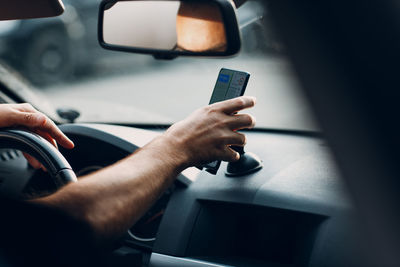 Midsection of man using mobile phone in car