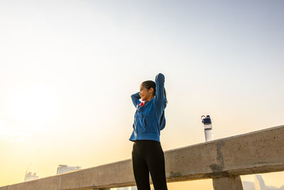 Low angle view of woman standing against clear sky