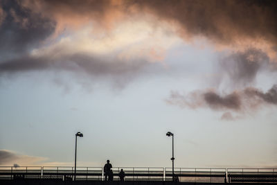 Man standing on railing of bridge