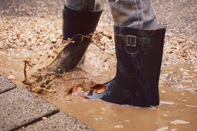 Low section of person standing in dirty puddle