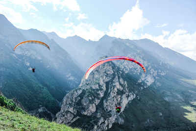 People paragliding on mountain peak against sky