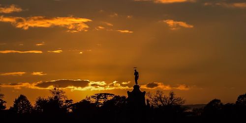 Silhouette statue against sky during sunset