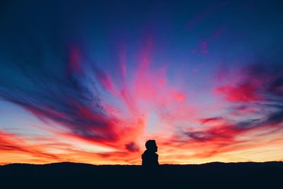 Silhouette person standing against dramatic sky during sunset