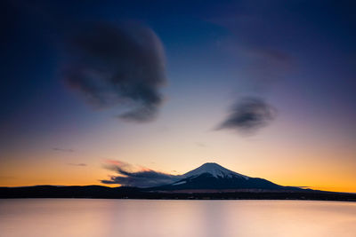 Scenic view of lake and mountains against sky during sunset