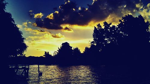 Silhouette of trees and lake at sunset