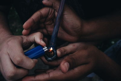 Cropped image of friends lighting smoking pipe