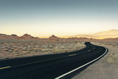 Empty road in desert against sky