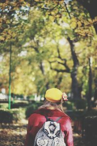 Rear view of woman walking through trees in park