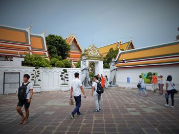 People outside temple against sky