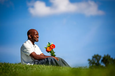 Full length of man sitting against blue sky