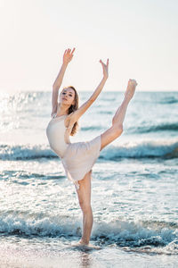 Portrait of beautiful woman dancing at beach against sea