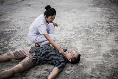 Nurse examining man lying outdoors