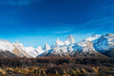 Scenic view of snowcapped mountains against blue sky