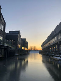 River amidst buildings against sky during sunset