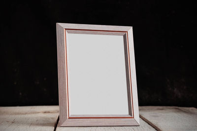 Close-up of empty picture frame on table against black background