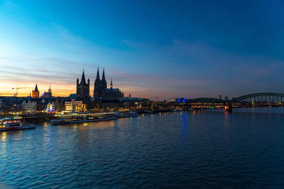 River and buildings in city at sunset